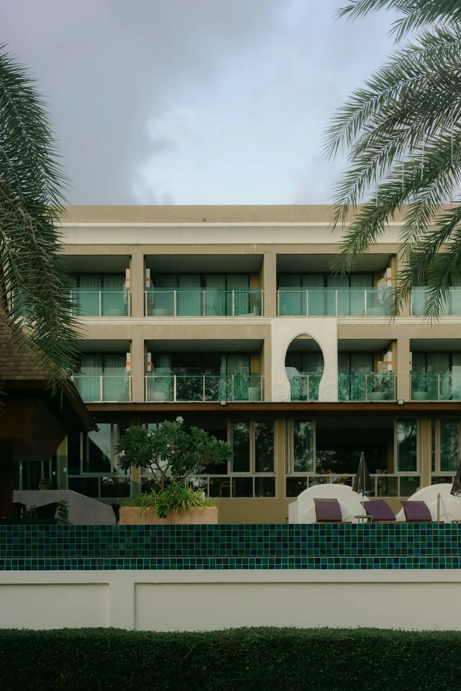 Hotel contemporâneo com varandas, palmeiras e piscina