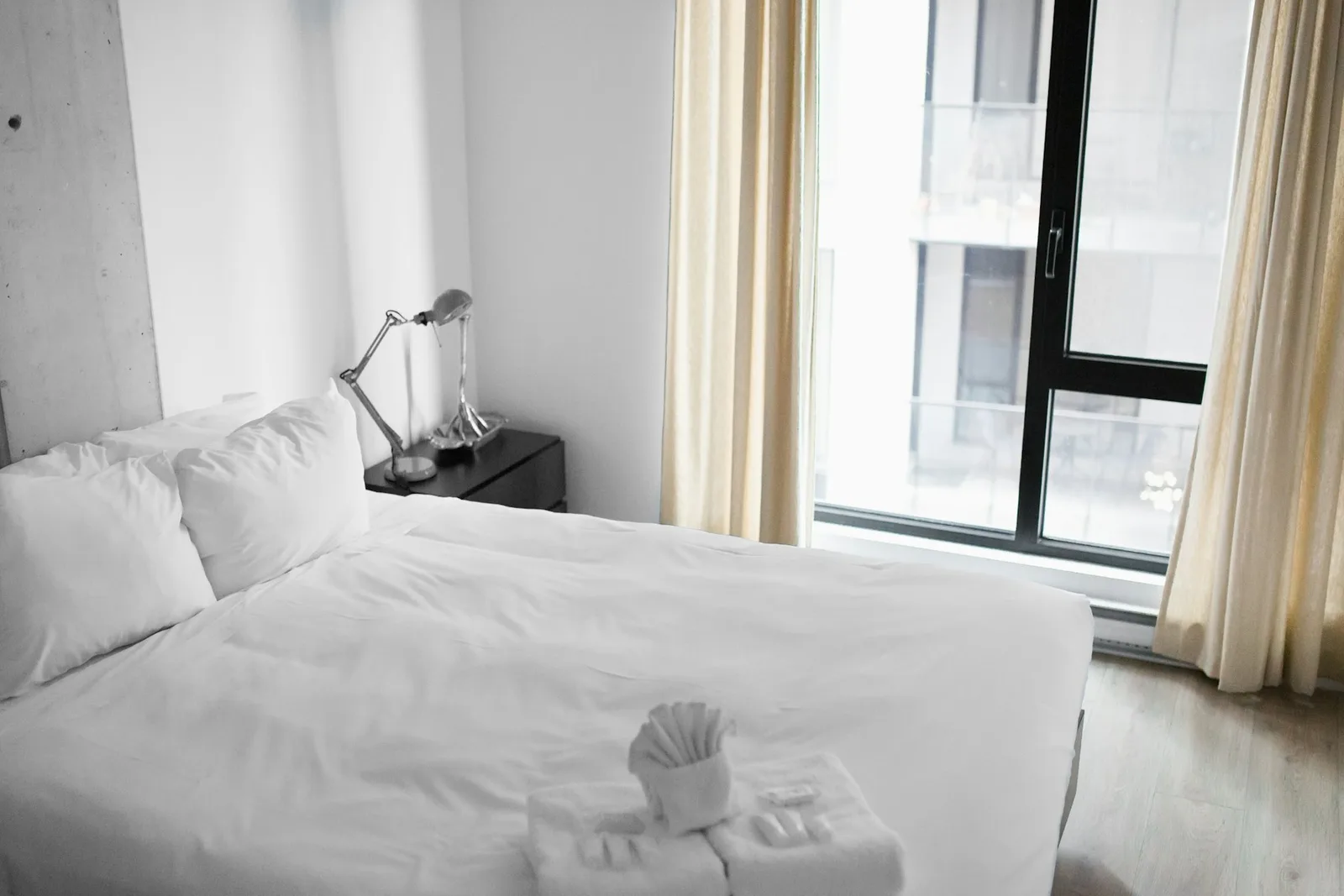 Quarto de hotel com cama de roupa branca junto à janela